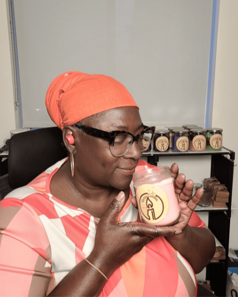 Woman smelling a home made candle with candles in the back ground